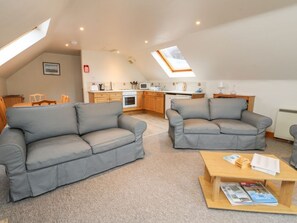 A loft-style living space with two grey sofas, a wooden coffee table, a kitchen area, and a skylight. - Wallace, Kinloch Rannoch (Pitlochry)