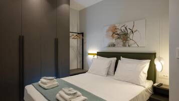 A hotel room with a bed, a nightstand, a wall-mounted lamp, a painting, and a wardrobe.