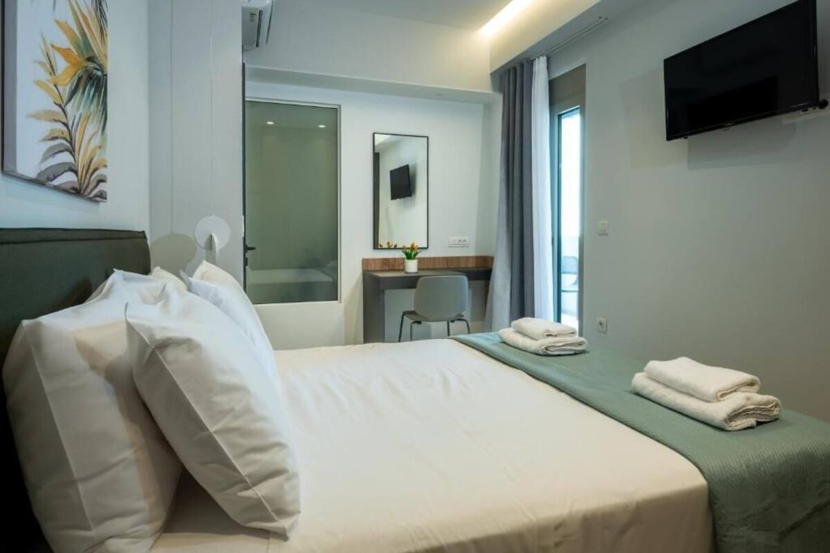 Une chambre d’hôtel avec un lit, un bureau, une chaise, une télévision et une fenêtre.