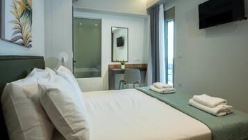 A hotel room with a bed, a desk, a chair, a TV, and a window.
