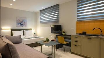Een moderne hotelkamer met een bed, nachtkastje, televisie, kitchenette en een eethoek.