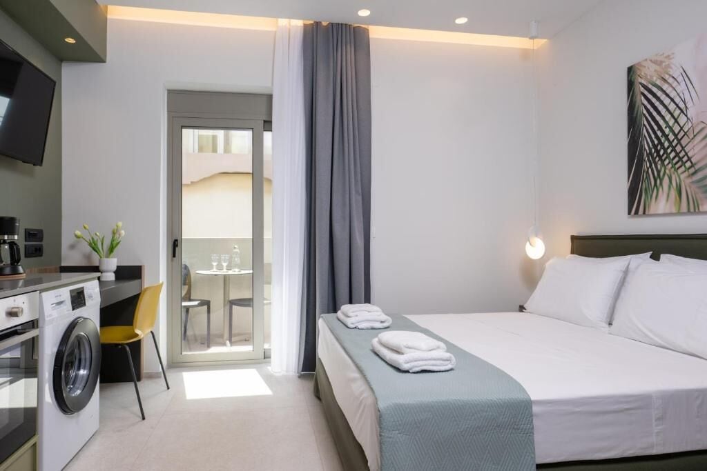 Hotellihuone, jossa on sänky, pesukone, ruokailutila ja televisio.
