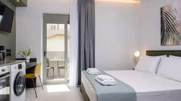 A hotel room with a bed, a washing machine, a dining area, and a TV.