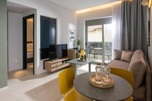 Un soggiorno moderno con divano, TV, tavolo da pranzo con sedie gialle e balcone con vista.
