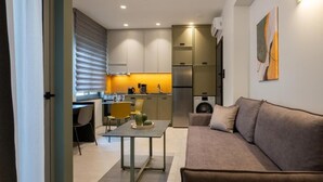 Eine moderne Küche mit integrierten Geräten, ein Essbereich mit Tisch und Stühlen sowie ein Wohnzimmer mit einer Couch.