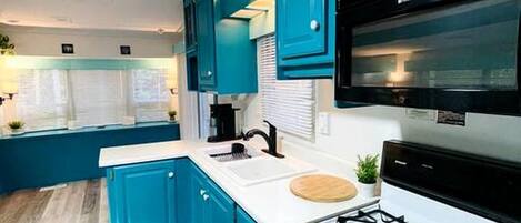 Una cocina moderna con armarios verde azulado, encimera blanca y estufa a gas.