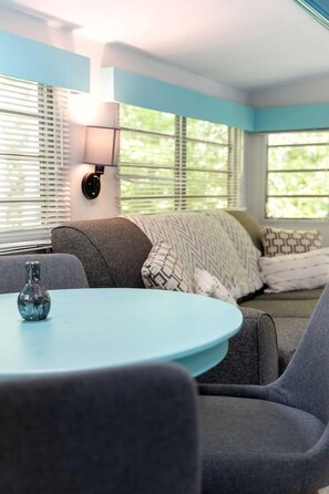 A cozy seating area with a round table, a lamp, and a vase. - Gorgeous and Unique Glamping Caravan near Miller Lake, Perfect for a Weekend of Swimming and Hiking (Miller Lake)