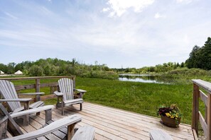 Una terraza de madera con sillas Adirondack y una planta en maceta.