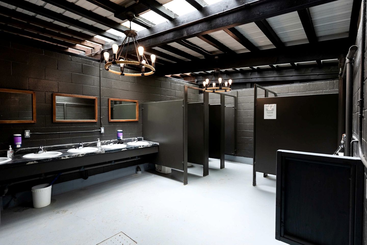 A public restroom with three sinks, mirrors, and a chandelier.