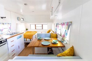 Una cucina compatta con zona pranzo, un letto e una finestra con tende.