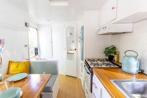 Una cucina compatta con piano cottura, lavello e zona pranzo con tavolo e sedie.