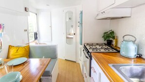 A compact kitchen with a stove, sink, and a dining area with a table and chairs.