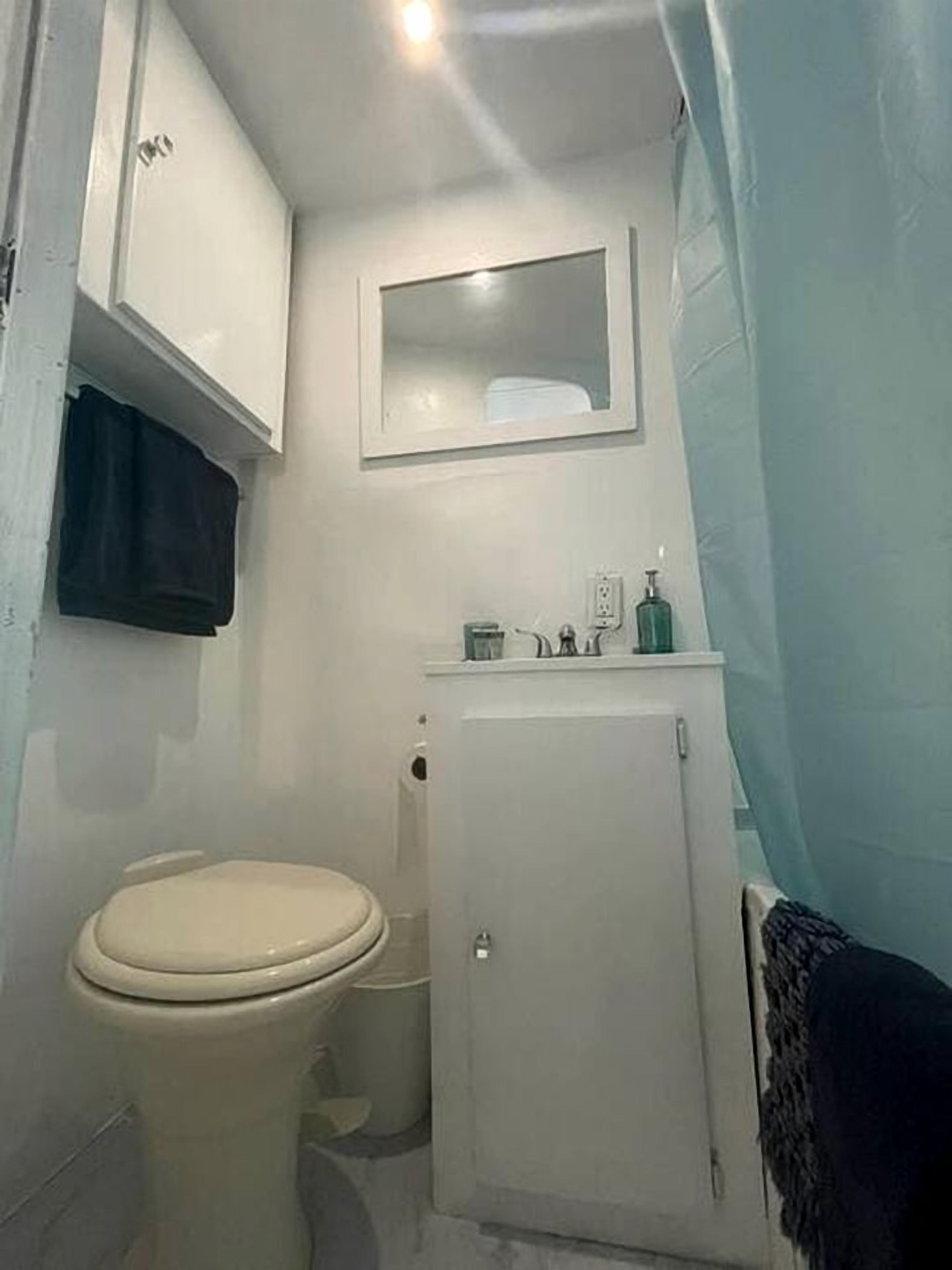 A small bathroom with a toilet, a cabinet, and a mirror.