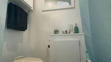 A small bathroom with a toilet, a cabinet, and a mirror.