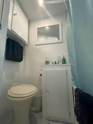 A small bathroom with a toilet, a cabinet, and a mirror.