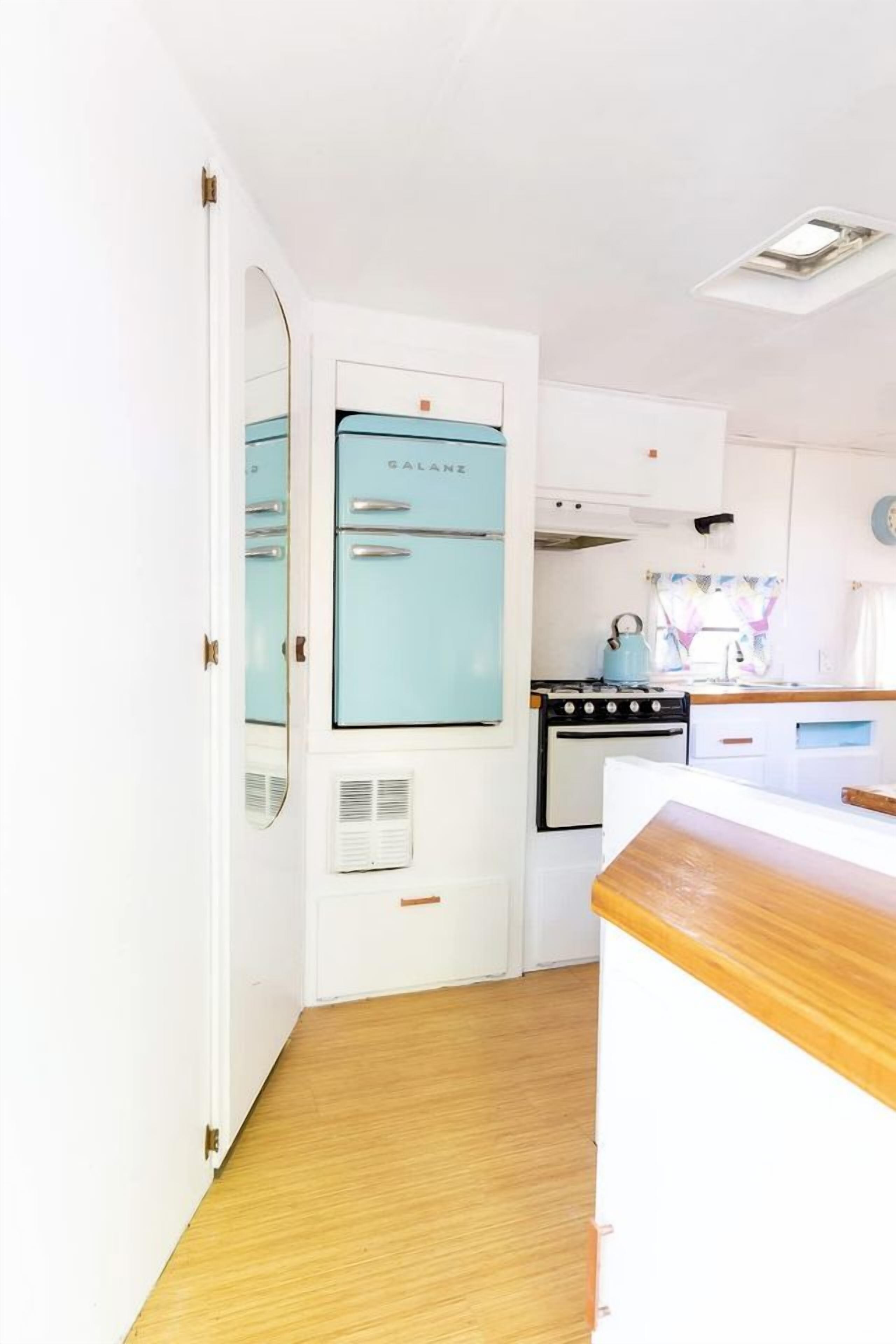 A compact kitchen with a vintage blue refrigerator, a stove, and a wooden countertop.