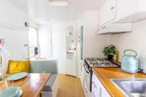 Uma cozinha compacta com fogão, pia e um espaço de refeições com mesa e cadeiras.