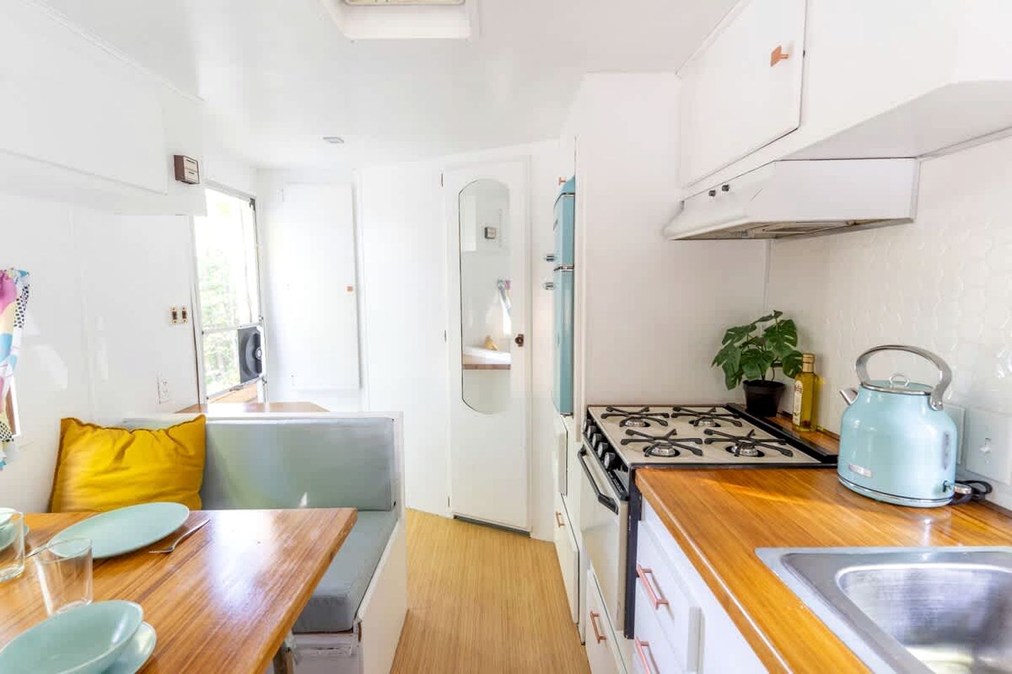Une cuisine compacte équipée d’une cuisinière, d’un évier et d’un coin repas avec une table et des chaises.