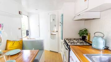 A compact kitchen with a stove, sink, and a dining area with a table and chairs.