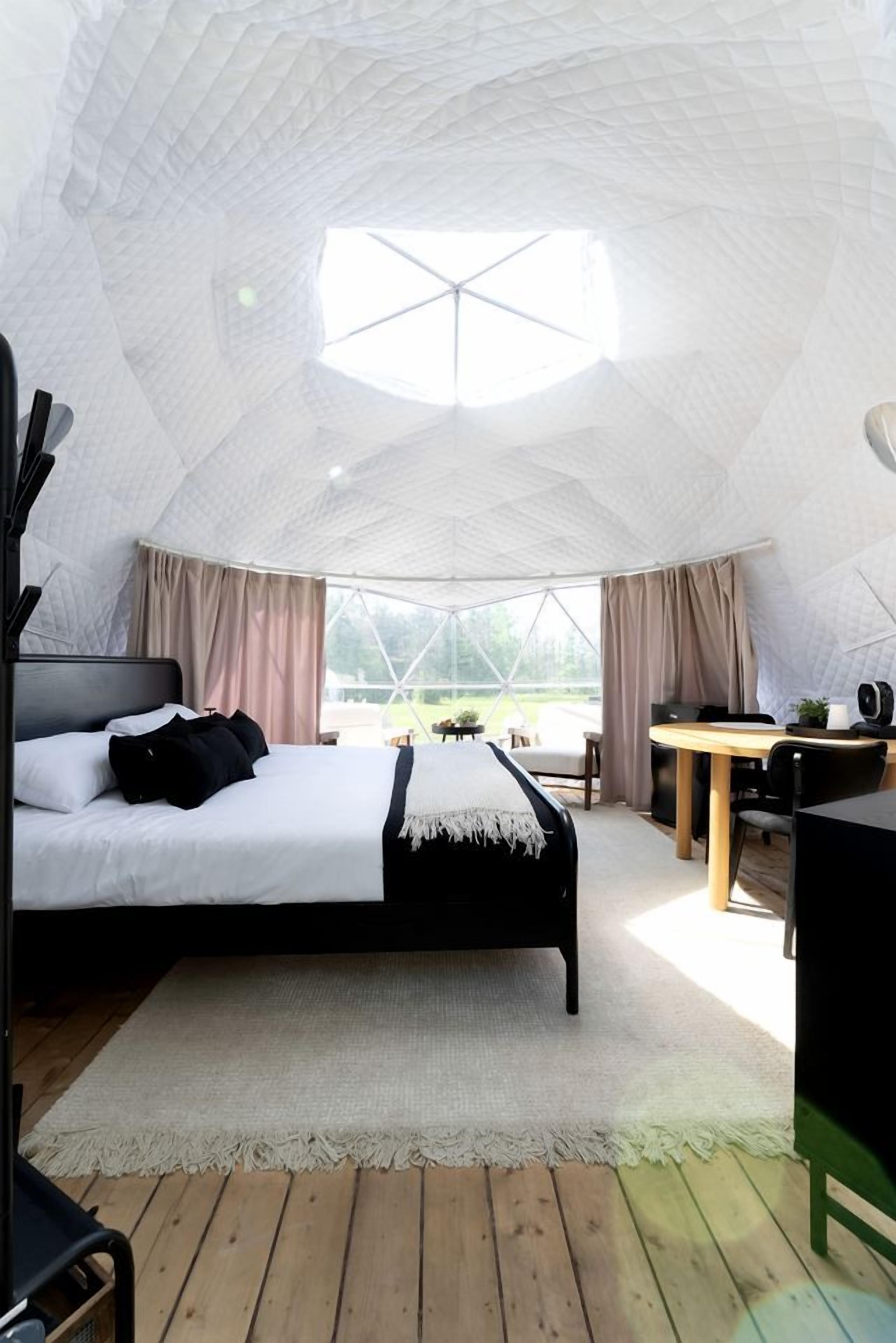 A tent-style room with a bed, a table, and a chair.