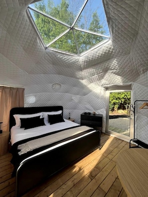 A bedroom with a bed, a bedside table, a wardrobe, and a skylight.