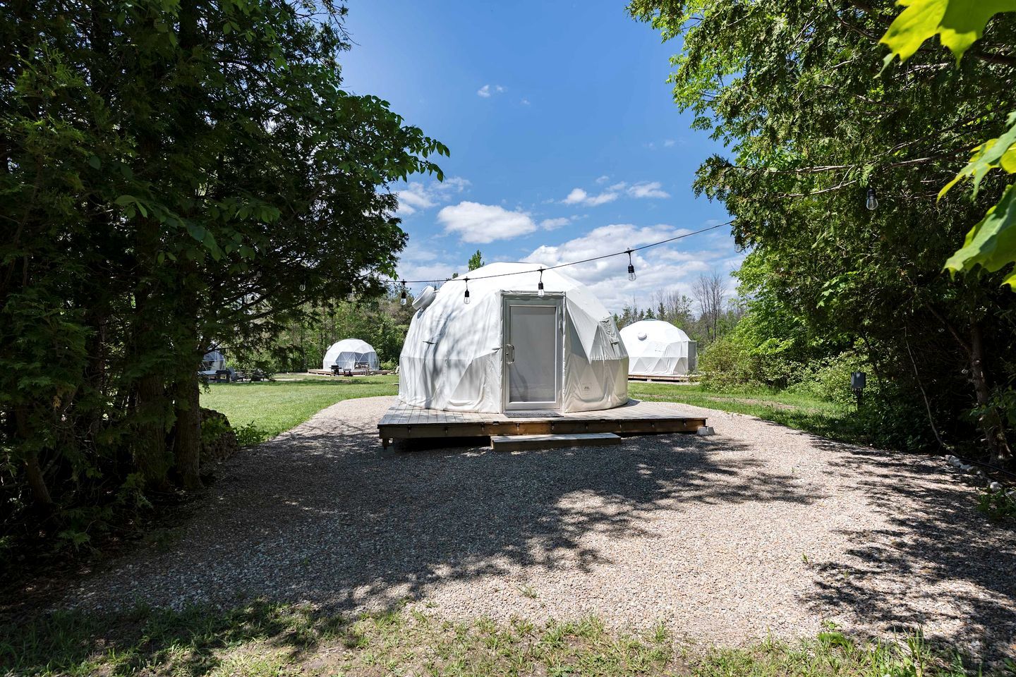 A covered outdoor area with a gravel path leading to a white tent-like structure.