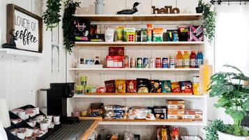 A kitchen with shelves stocked with various food items, a coffee machine, and a 'lover of coffee' sign.
