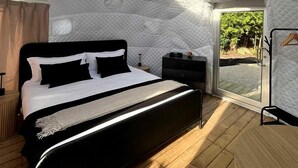 Un dormitorio con cama, mesita de noche, armario y tragaluz.