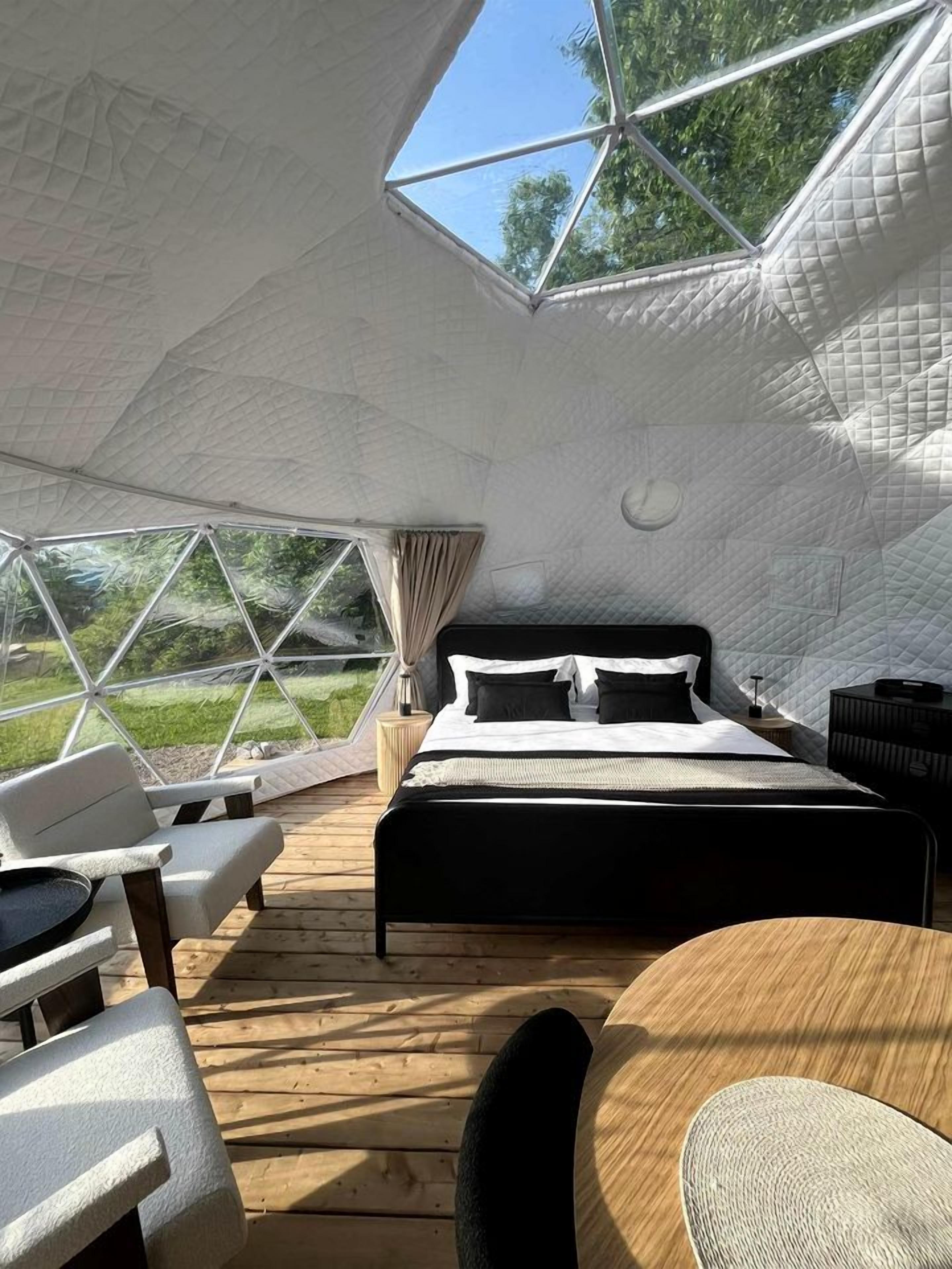 Une pièce en forme de dôme, comprenant un lit, un coin salon et offrant une vue sur l’extérieur.