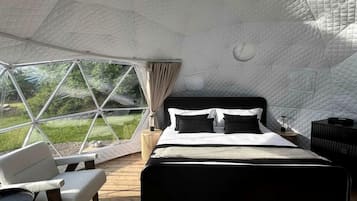 A dome-shaped room with a bed, seating area, and a view of the outdoors.