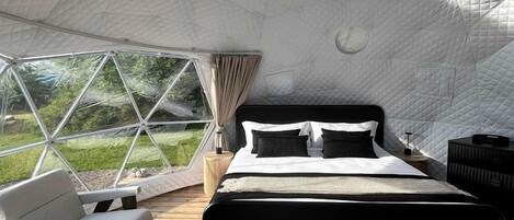 Una habitación de forma abovedada con cama, zona de estar y vistas al exterior.