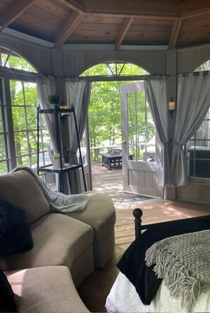 A cozy room with a sofa, a bed, a small table, and a window with curtains.