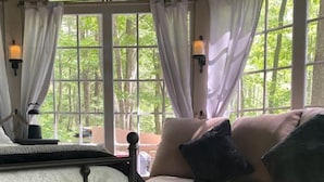 A cozy room with a sofa, ottoman, and a table with a lamp.