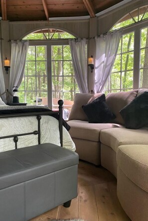 A cozy room with a sofa, ottoman, and a table with a lamp.