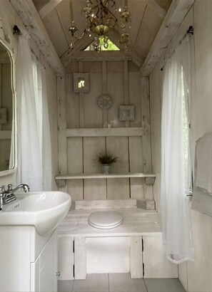 A rustic bathroom with a wooden vanity, a sink, a toilet, and a chandelier.