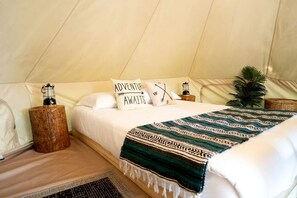 A tented accommodation room with a bed, pillows, a blanket, a lantern, and a small plant. - Tranquil Forest Oasis: Fabulous Bell Tent for Two near Tobermory, Canada (Northern Bruce Peninsula)