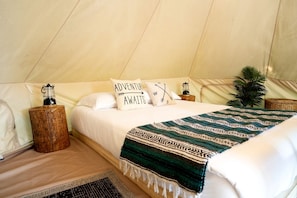 A tented room with a bed, pillows, a lantern, and a woven blanket. - Tranquil Forest Oasis: Fabulous Bell Tent for Two near Tobermory, Canada (Northern Bruce Peninsula)