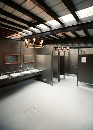 A public restroom with marble sinks, wooden beams, and pendant lighting.