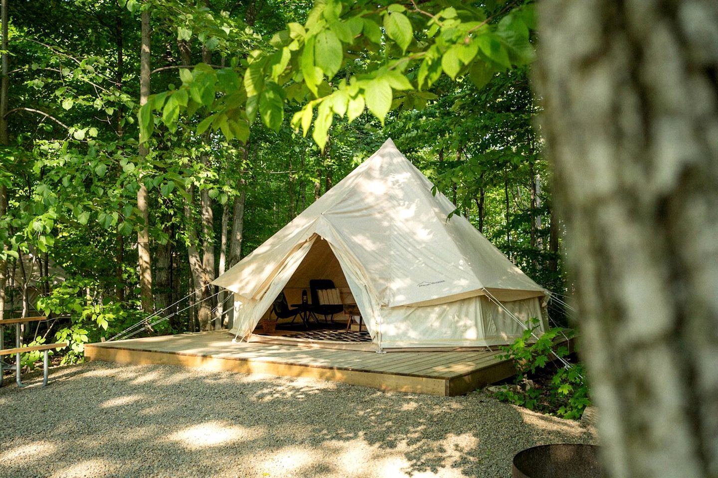 A tent with a wooden deck in a forested area.
