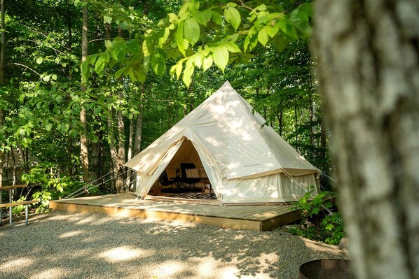 A tent with a wooden deck in a forested area.