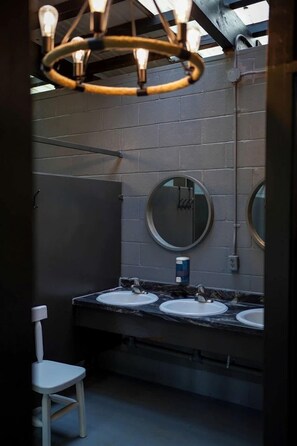 Des toilettes publiques équipées de trois lavabos, de deux miroirs et d’un luminaire suspendu.