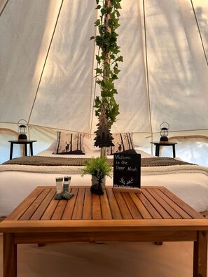 A tent with a bed, a welcome sign, a small table with a plant, and two lanterns. - Intimate Luxurious Bell Tent with Fire Pit in Ontario (Northern Bruce Peninsula)