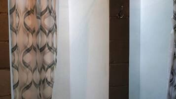 A bathroom with a shower curtain, a tiled wall, and a small window.
