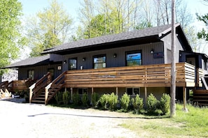 A two-story building with a wooden deck and stairs leading to the entrance.