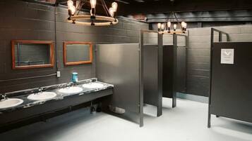 A restroom with marble sinks, wooden-framed mirrors, and exposed ceiling beams.