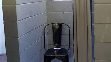 A corner room with a black chair, beige curtains, and a metal rod.
