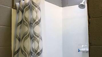 Eine Dusche mit transparenter Duschvorhang und Handbrause.
