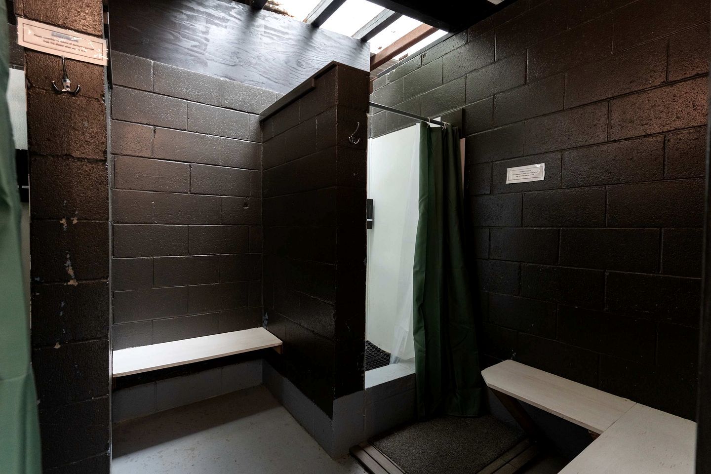 A small, dark-walled bathroom with a bench and a shower curtain.