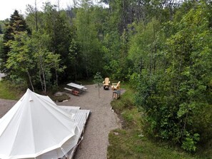 A campsite with tents, a table, chairs, and a gravel path surrounded by trees.