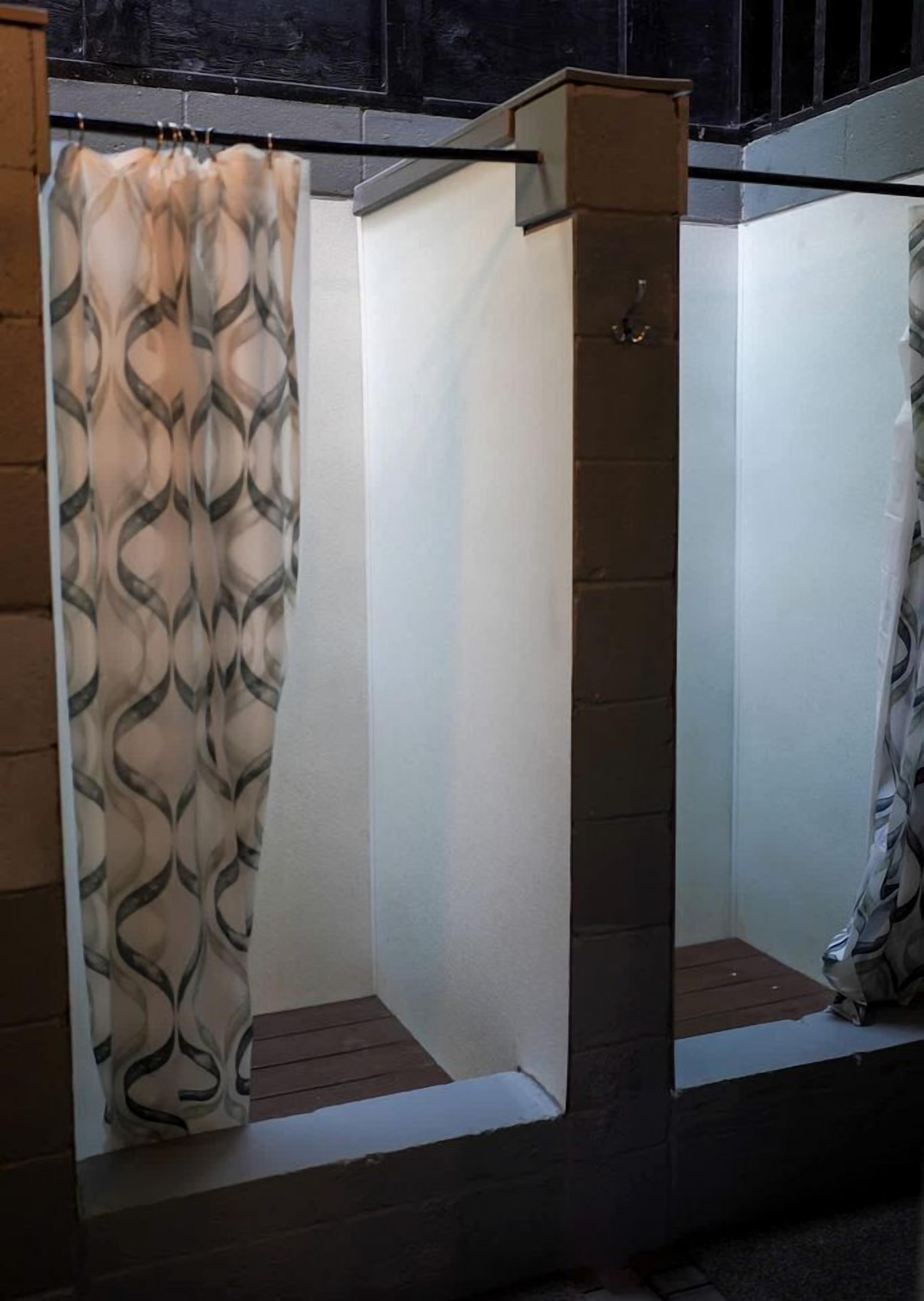 A bathroom with a shower curtain, a white wall, and a small window.